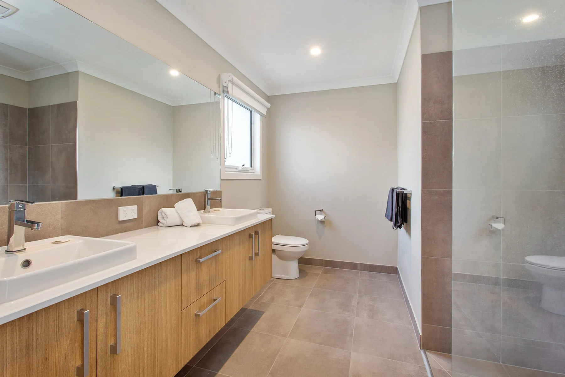 A spacious bathroom with a long vanity and a glass shower.