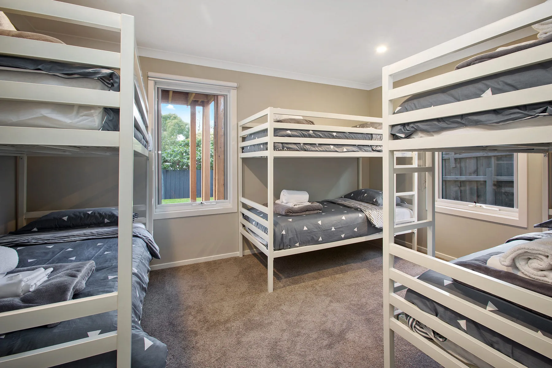 A bedroom with several bunk beds and windows.