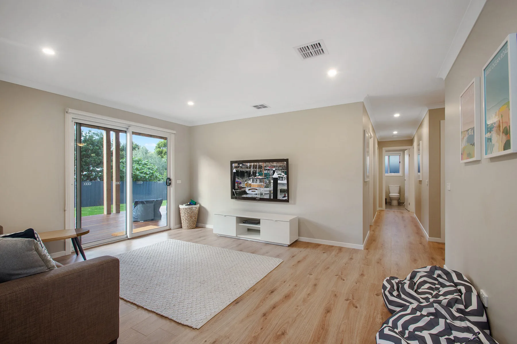 A living room with a television, a rug, and sliding glass doors.