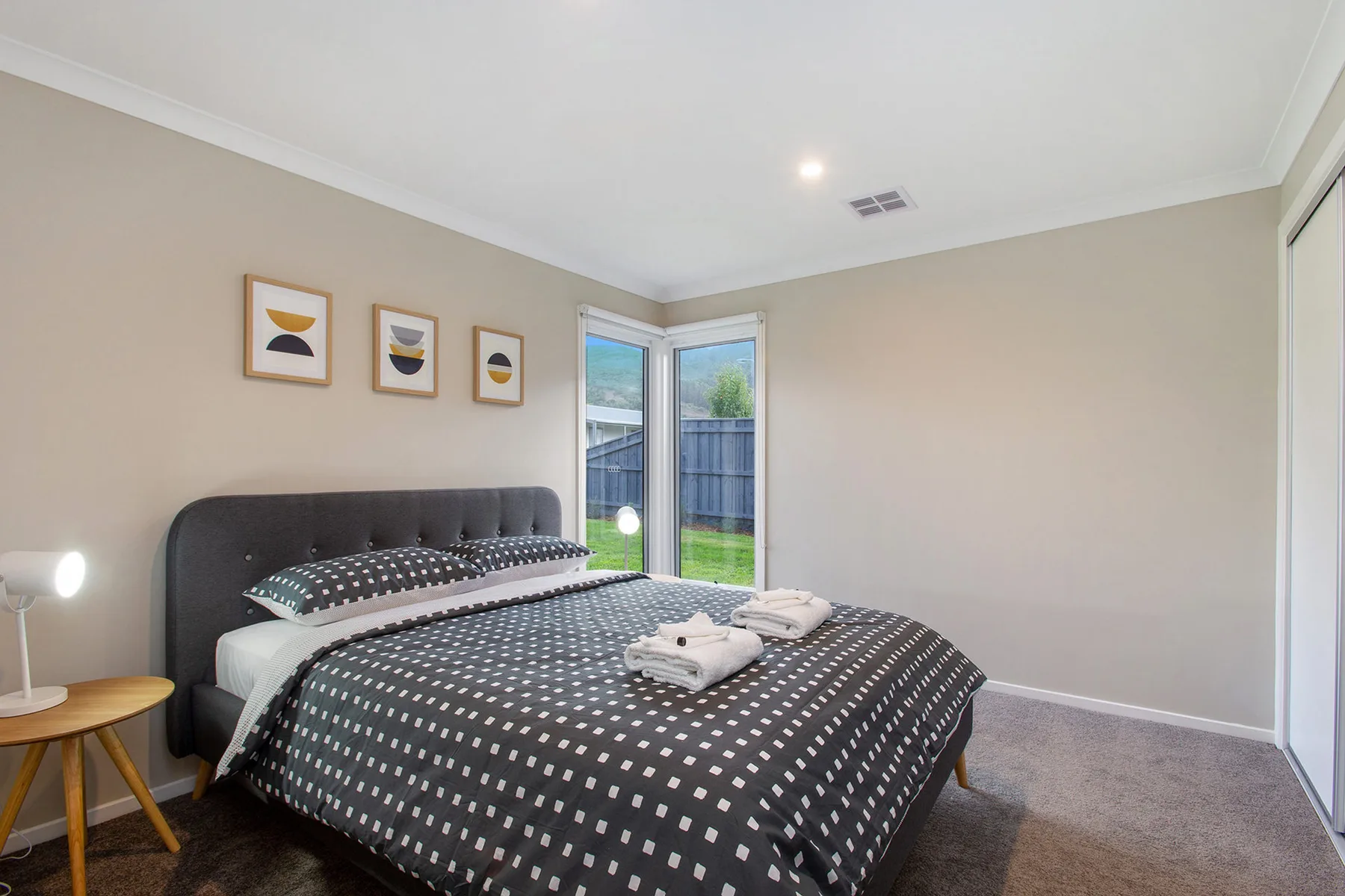 A bedroom with a neatly made bed and glass doors opening onto a small outdoor area.