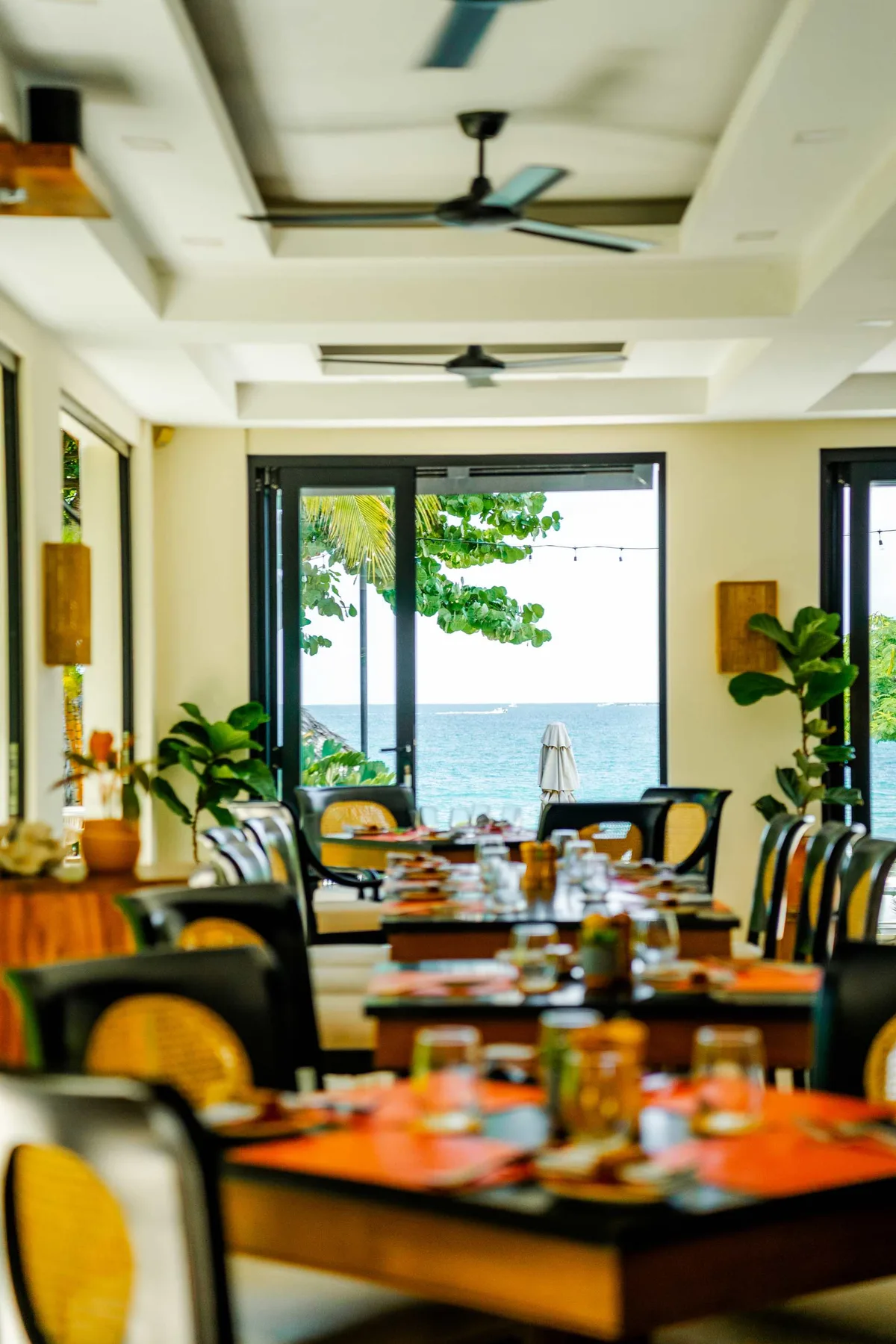 Zona común: Un comedor con mesas y asientos junto a grandes ventanas con vistas al agua.