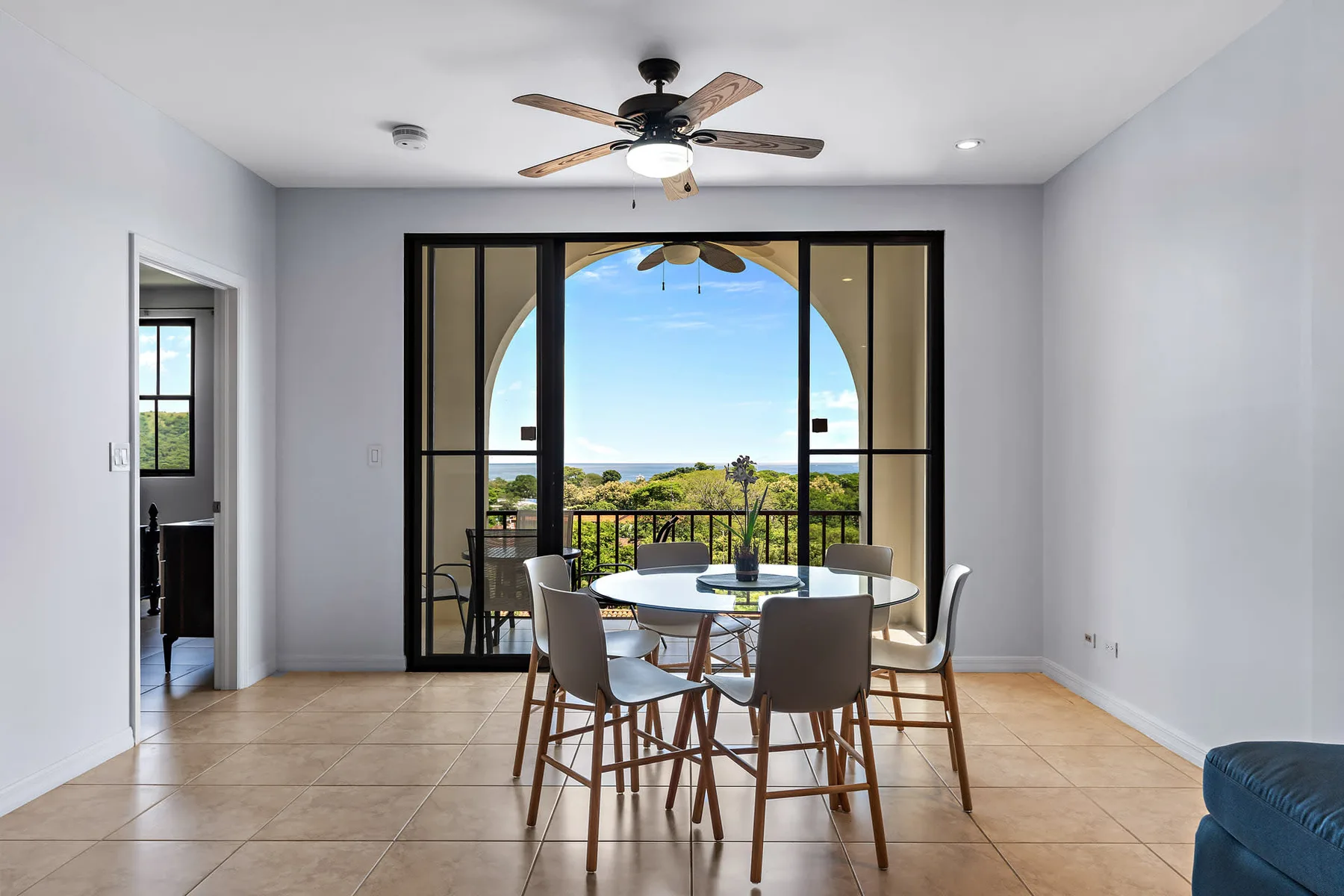 Comedor con mesa y sillas frente a grandes puertas de vidrio y una vista panorámica.