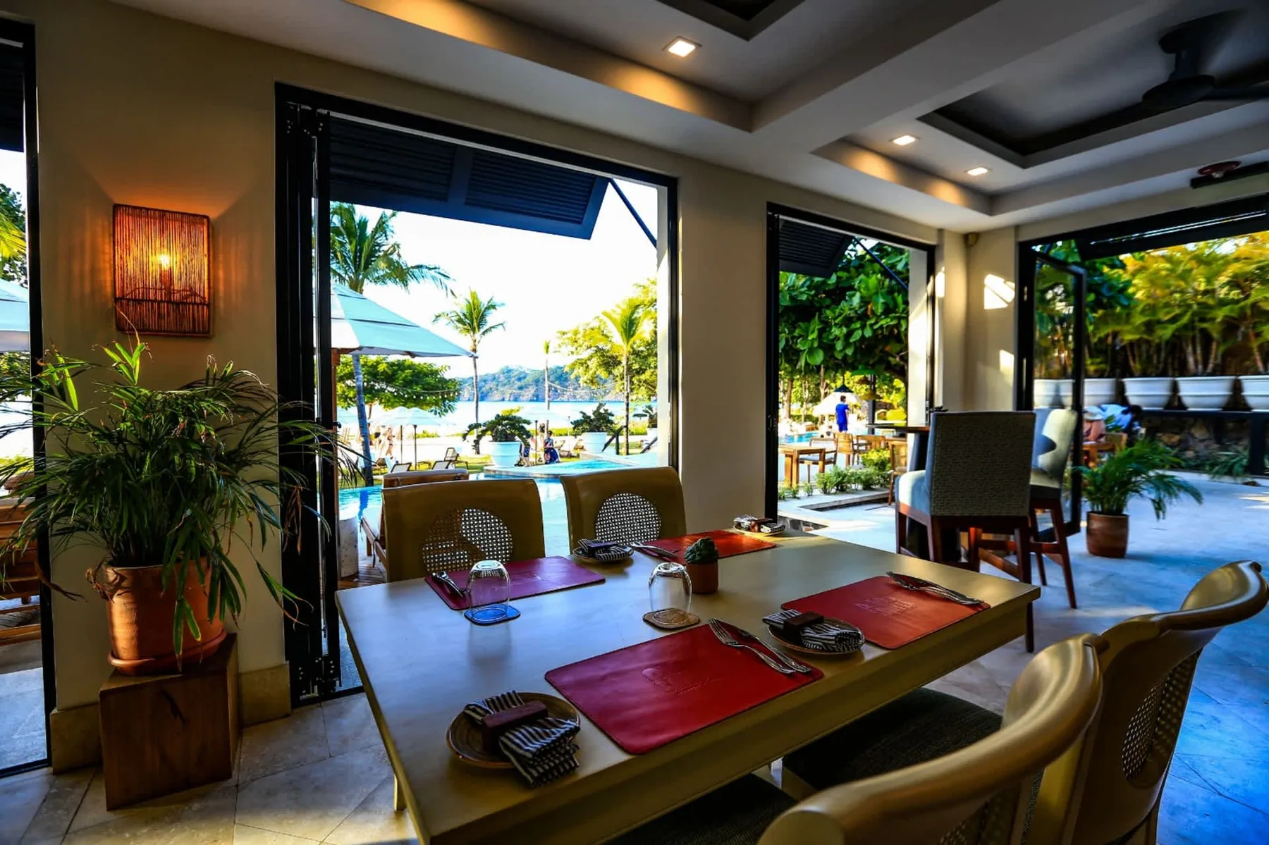 Zona común: Un comedor se abre a un patio con plantas tropicales y una piscina.
