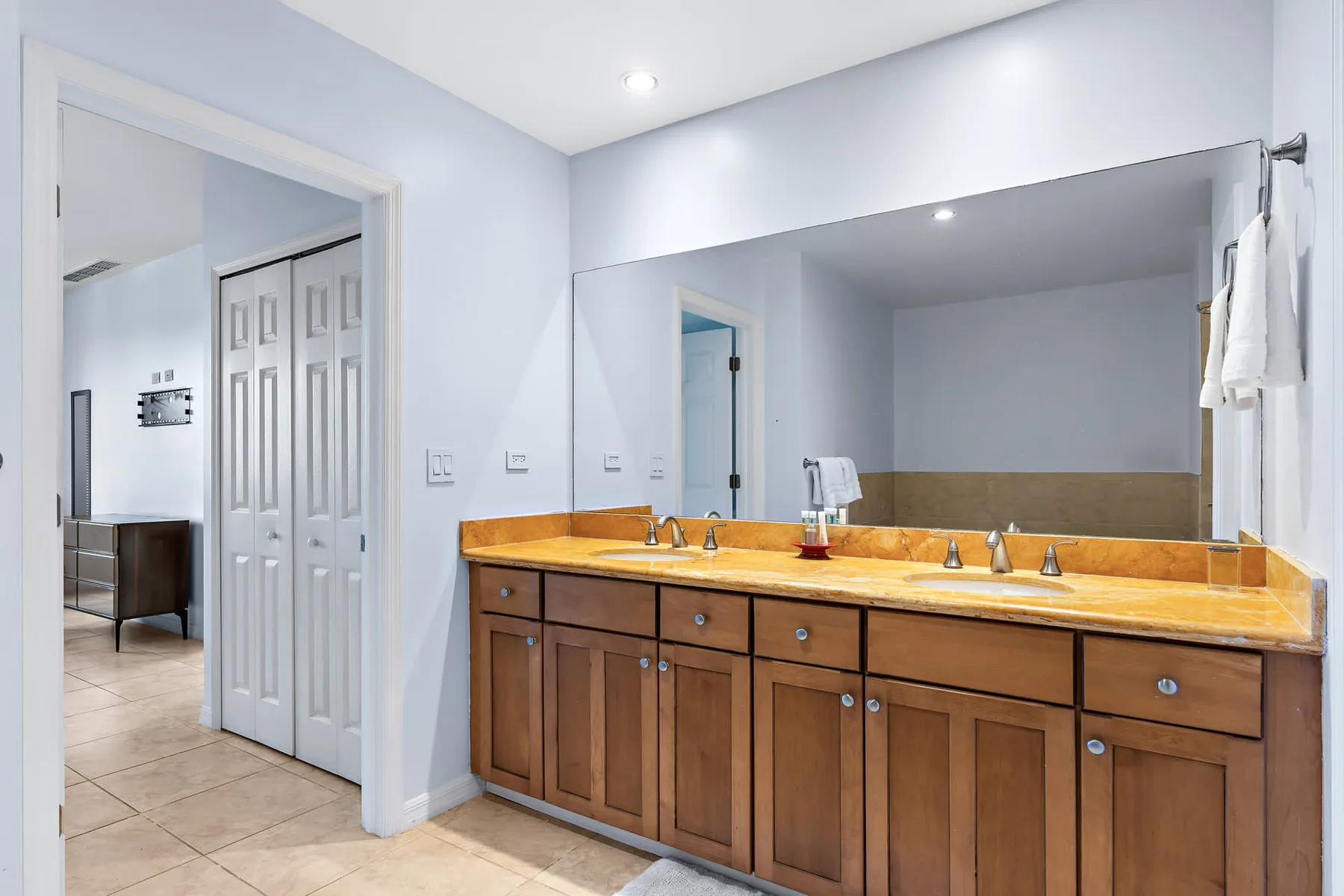 Un tocador de baño con un espejo largo y gabinetes de madera.