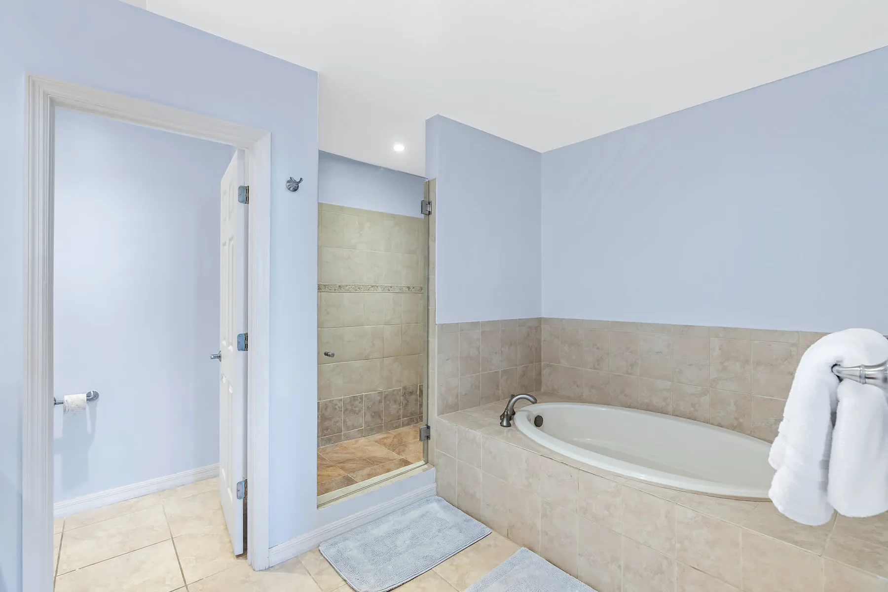 Baño con bañera, ducha y paredes de azulejos.