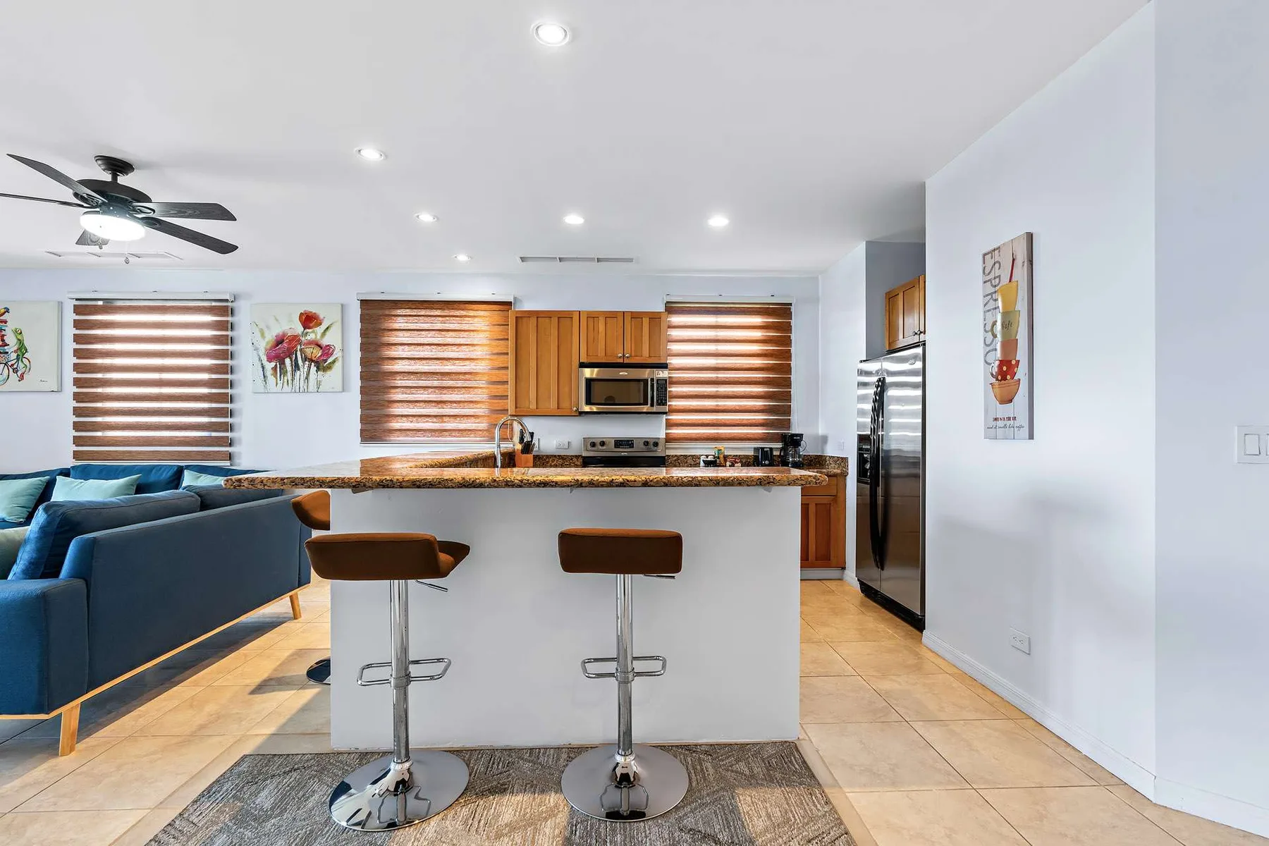 Una cocina luminosa con una isla para desayunar y asientos junto a un sofá azul.