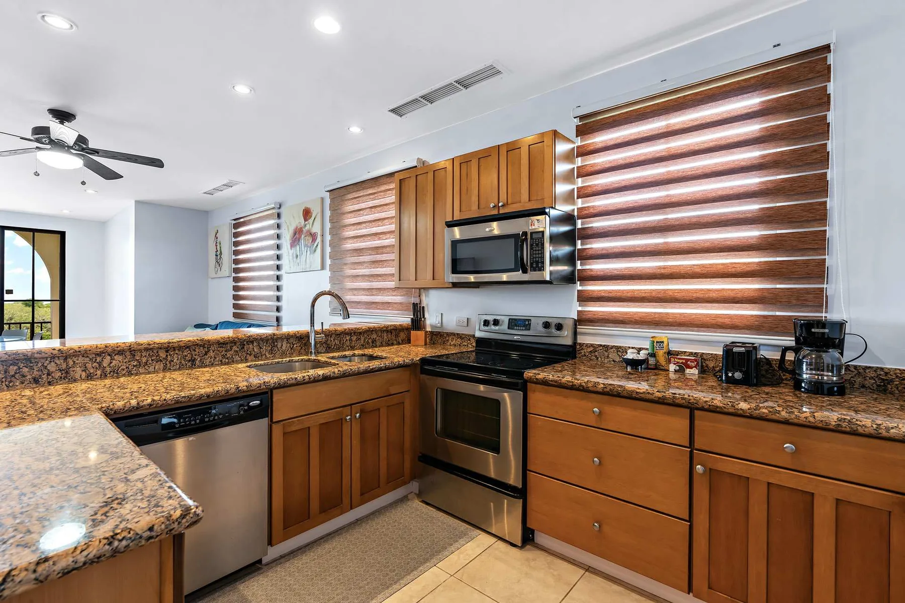 Una cocina luminosa con gabinetes de madera, encimeras de piedra y una estufa de acero inoxidable.