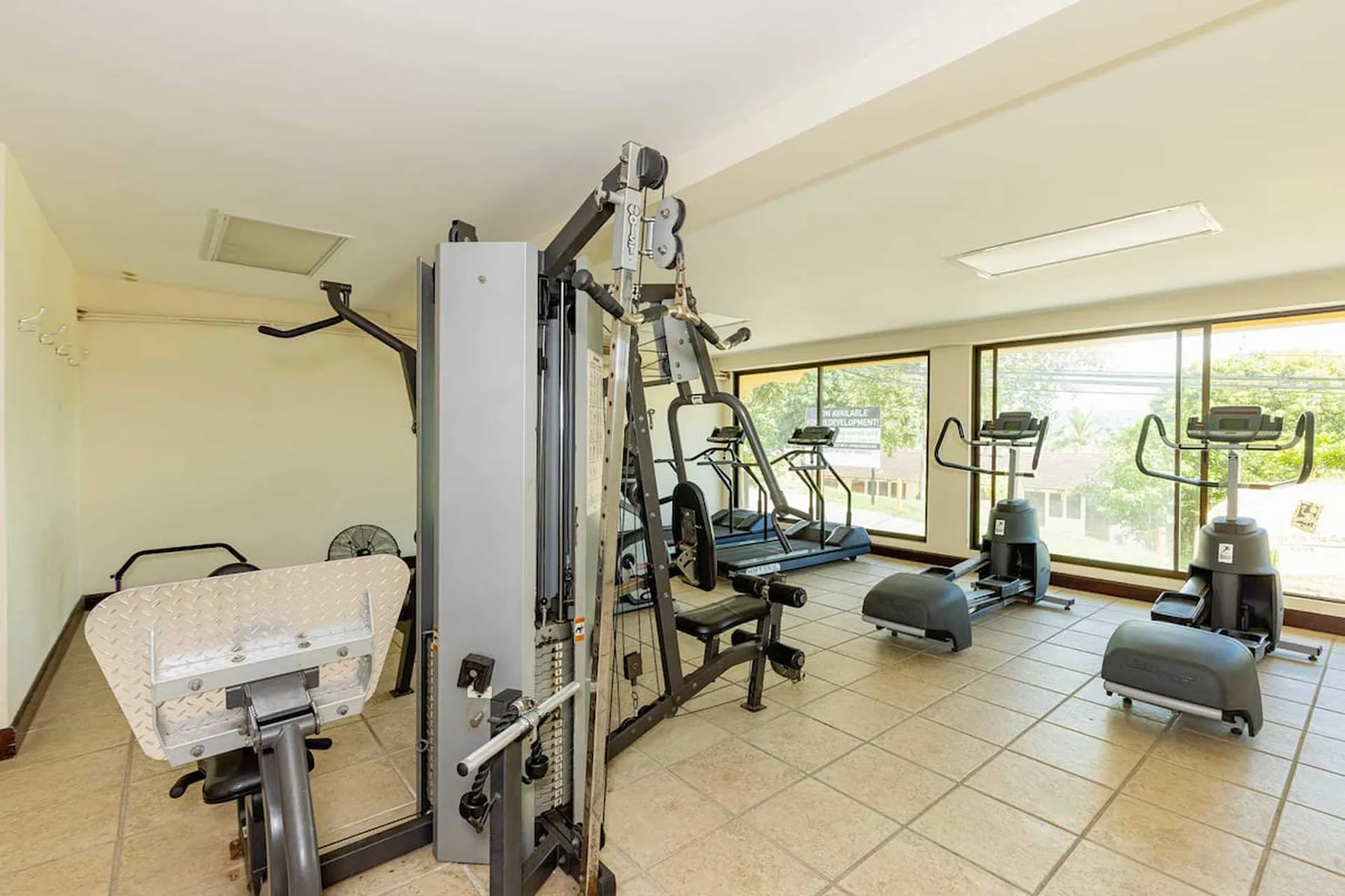 Zona común: Un gimnasio con máquinas de ejercicio y grandes ventanas.