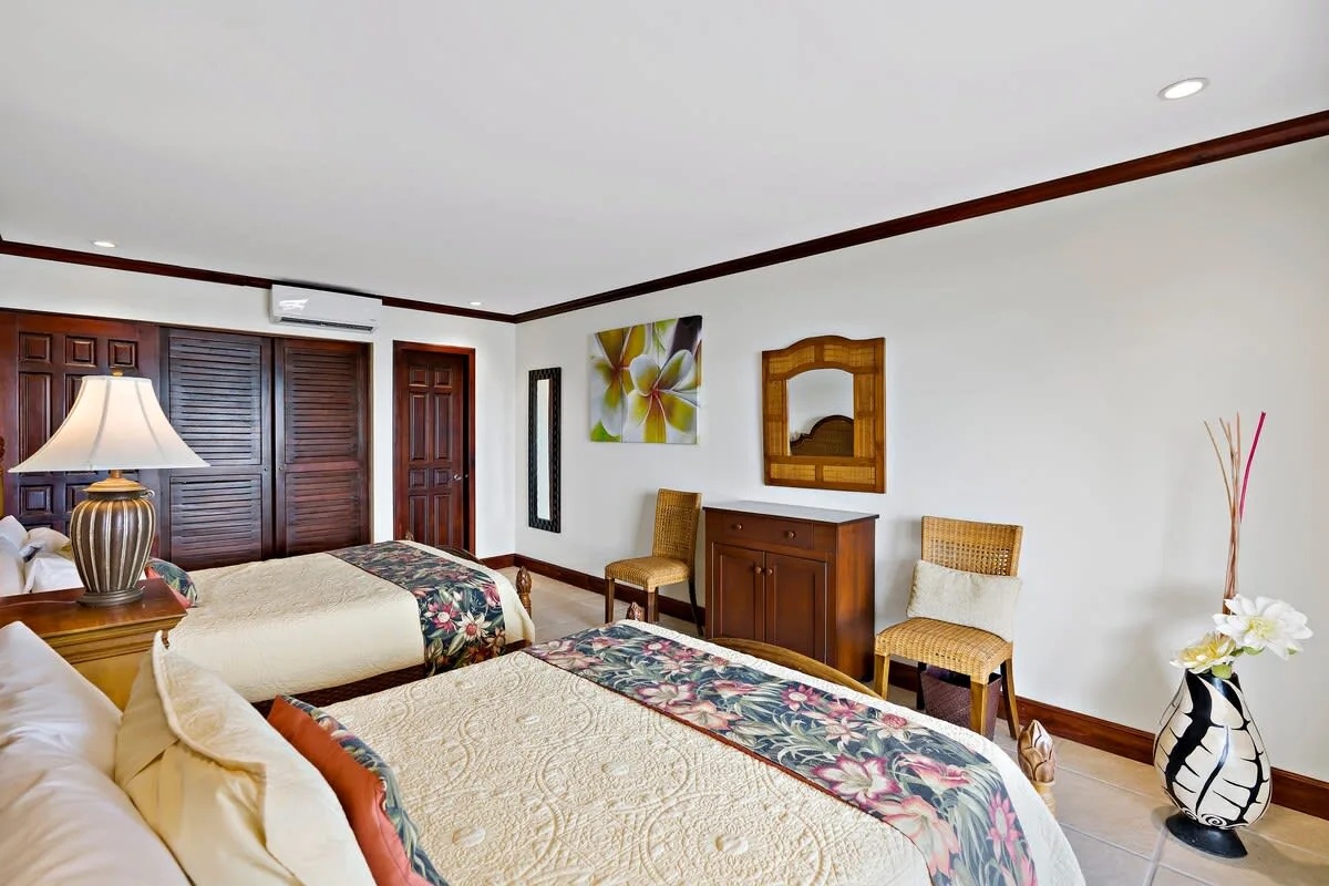 Un dormitorio con dos camas, muebles de madera y arte floral en la pared.