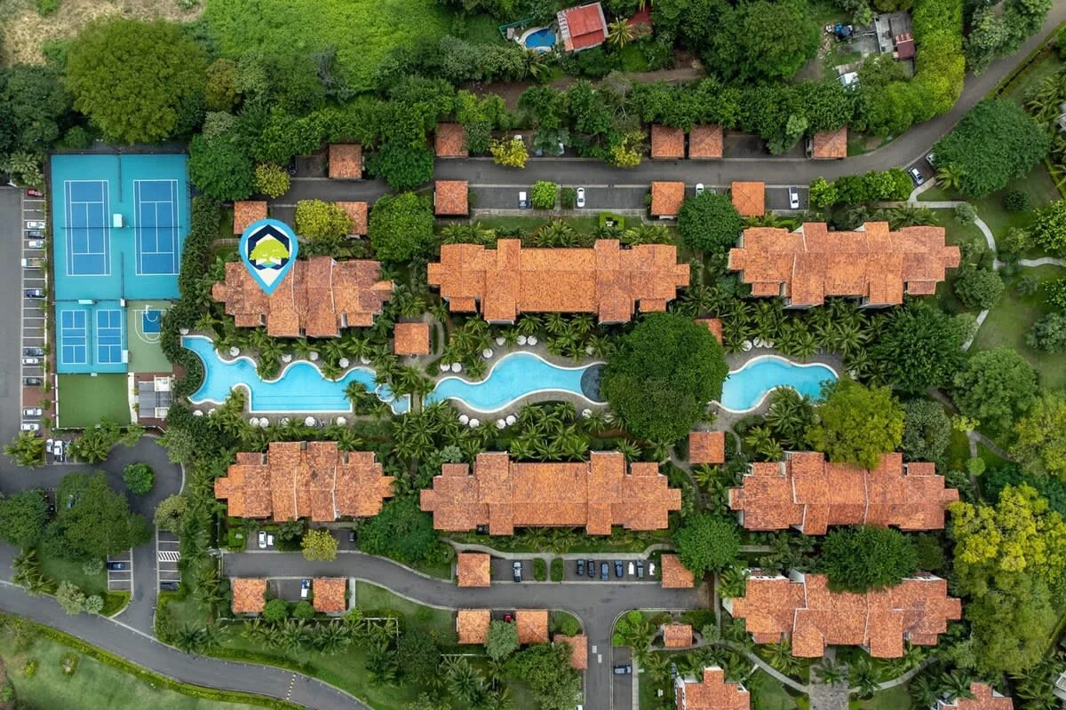 Zona común: Vista aérea de un complejo ajardinado con piscinas y canchas de tenis.