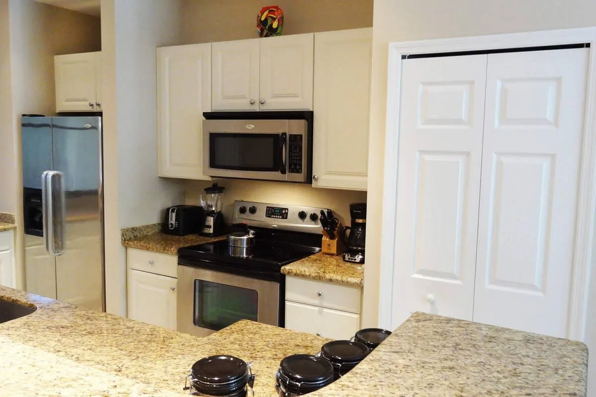 Una cocina con gabinetes blancos, electrodomésticos de acero inoxidable y encimeras de granito.