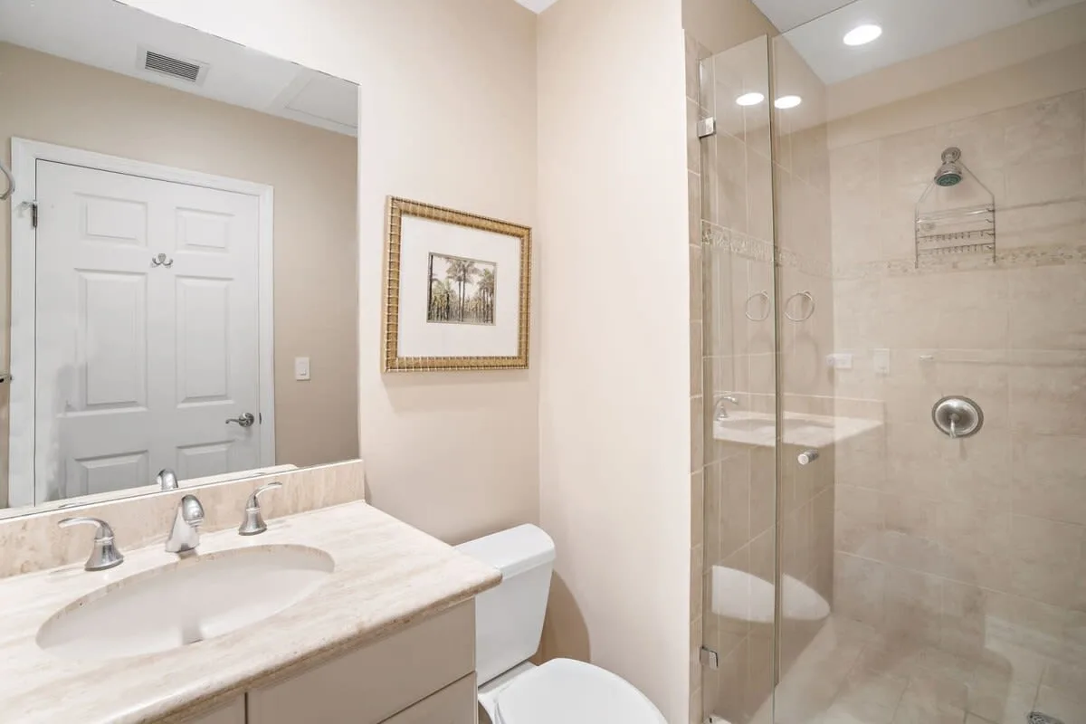 Un baño con lavabo, inodoro y ducha con mampara de vidrio.