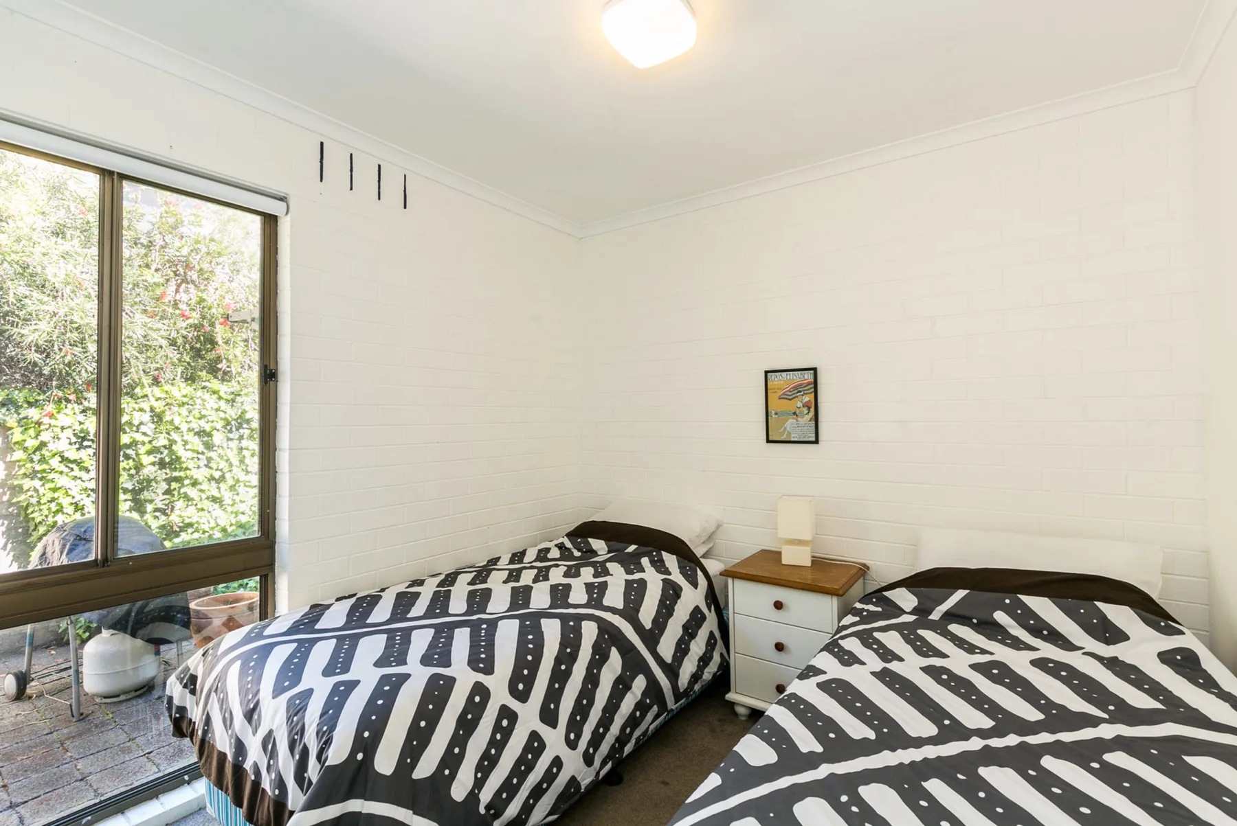 Un dormitorio con dos camas cubiertas con ropa de cama estampada en blanco y negro.