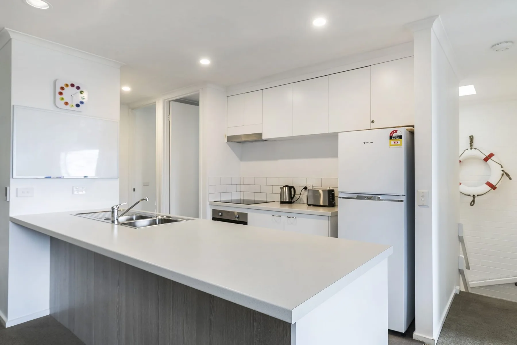 Cocina con gabinetes blancos, refrigerador y una amplia encimera.