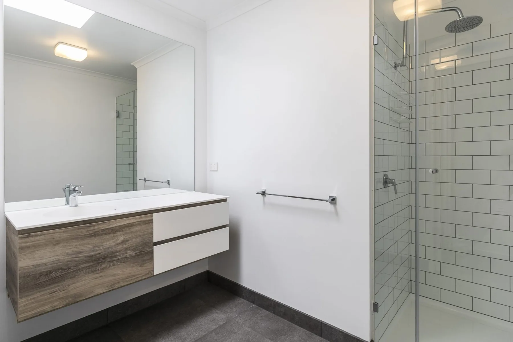 Un baño moderno con lavabo suspendido y ducha revestida de azulejos.