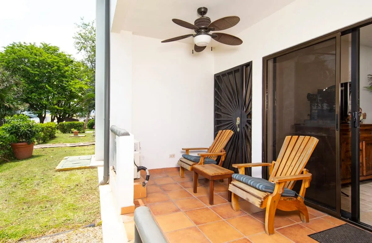 A covered patio with wooden seating and dark sliding glass doors.