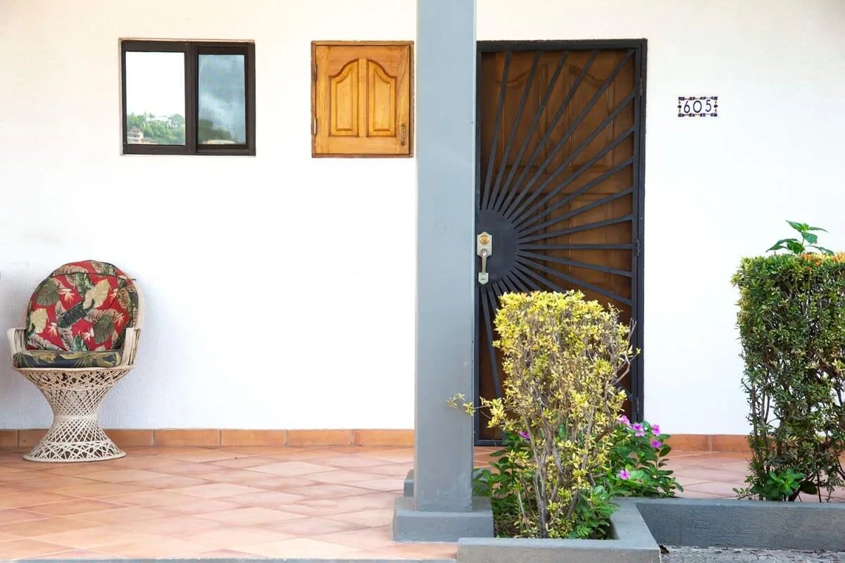 Shared amenity: A tiled outdoor entryway with a dark metal gate and potted greenery.