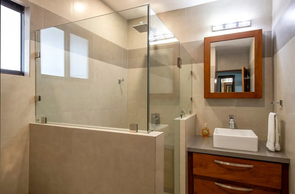 A modern bathroom with a glass shower and a sink beneath a wall mirror.