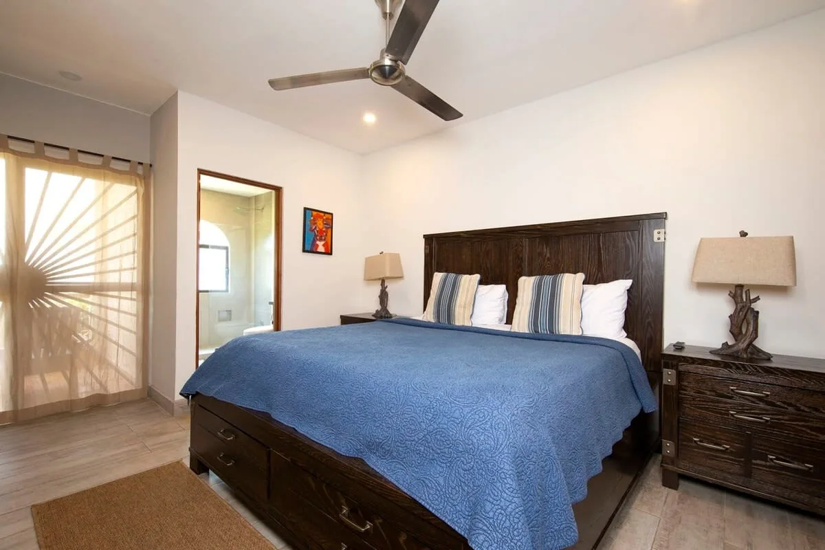 A bedroom with a large bed covered by a blue bedspread.