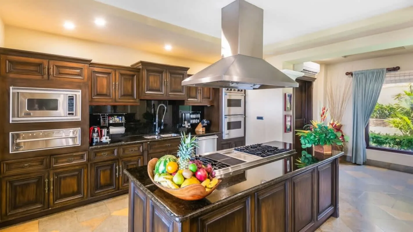 A spacious kitchen with dark wood cabinets, a central island, and a large range hood.