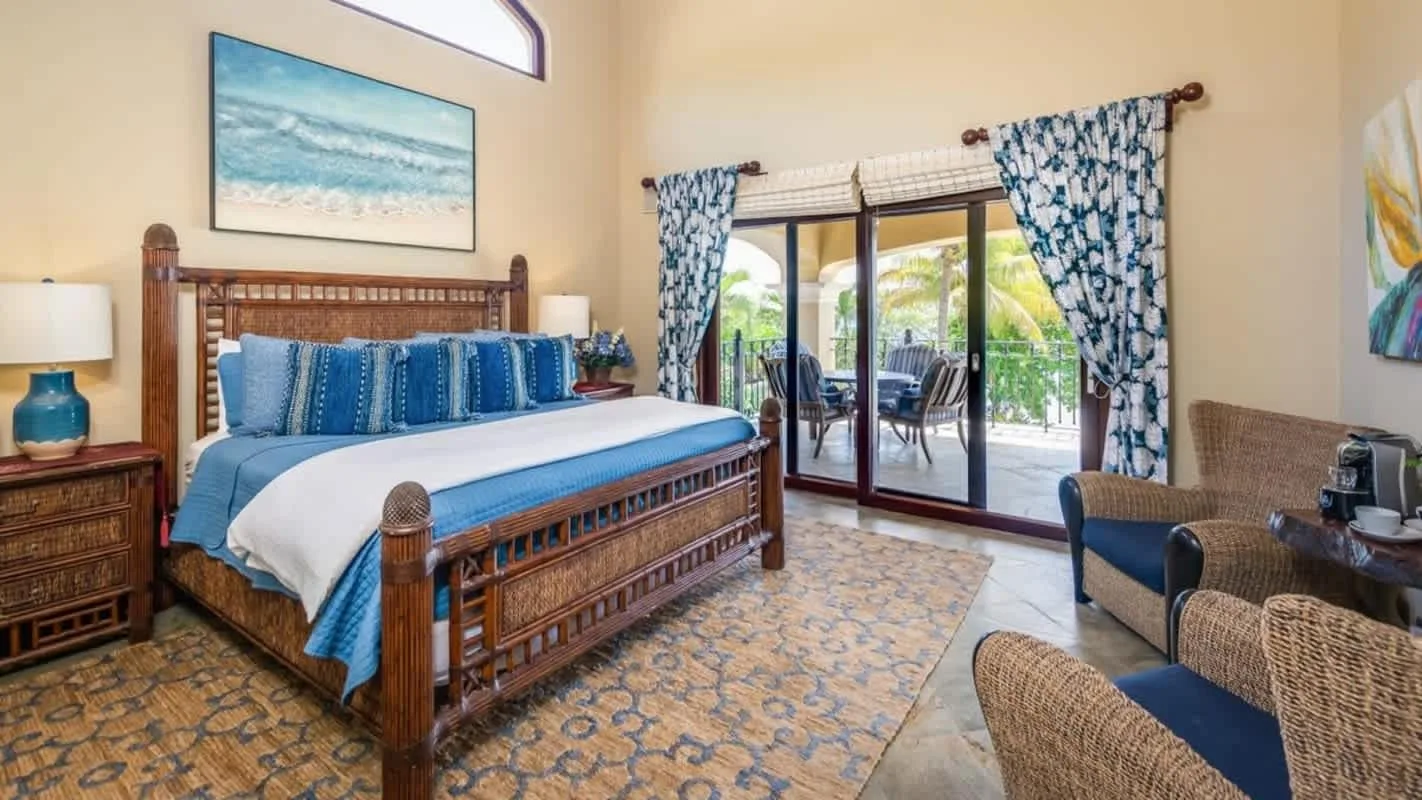 A bedroom with a large bed, blue accents, and glass doors opening onto a patio.