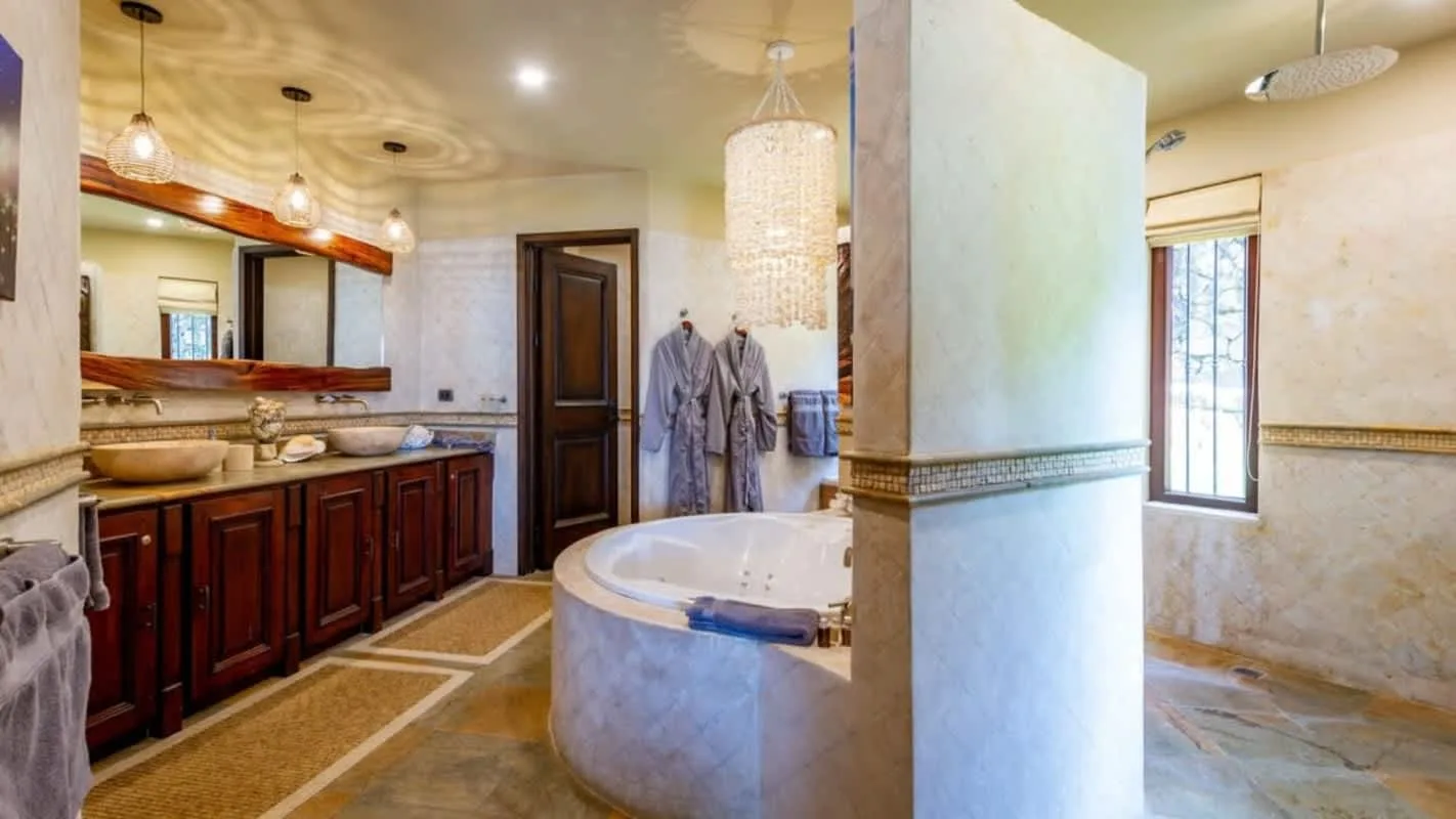 A bathroom with a vanity, a large mirror, and a bathtub.
