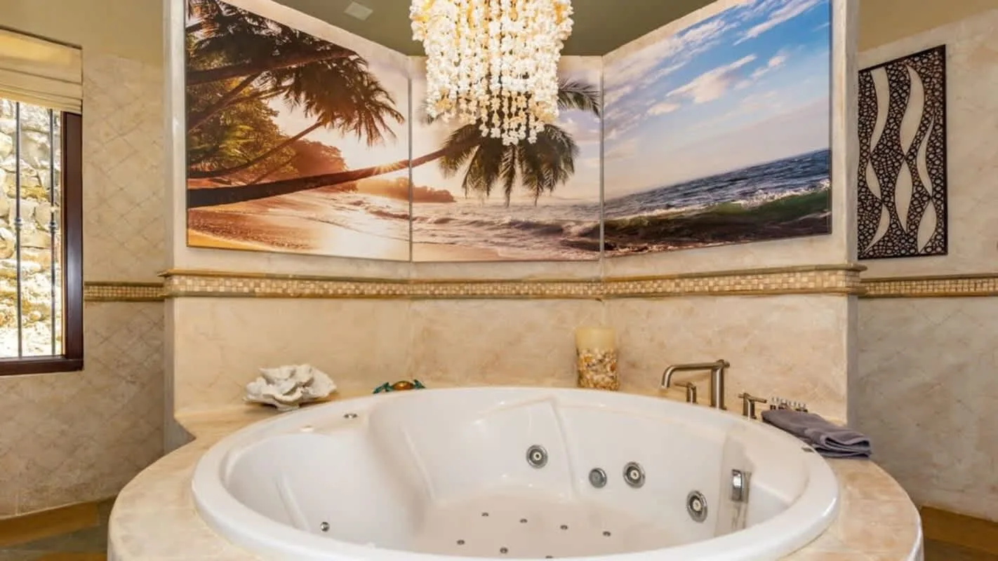 A bathroom features a large round jetted tub beneath a beach mural.