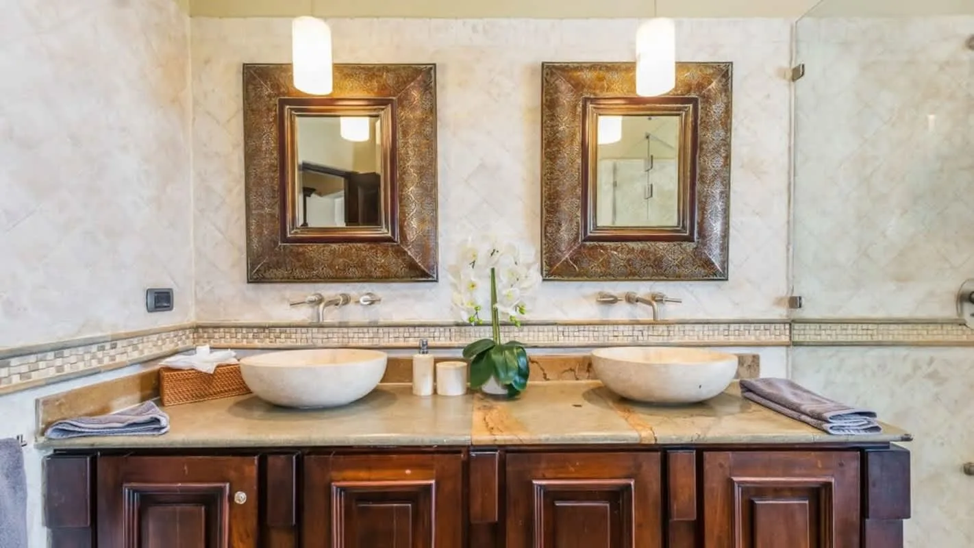 A bathroom vanity with two sinks, framed mirrors, and towels on the counter.