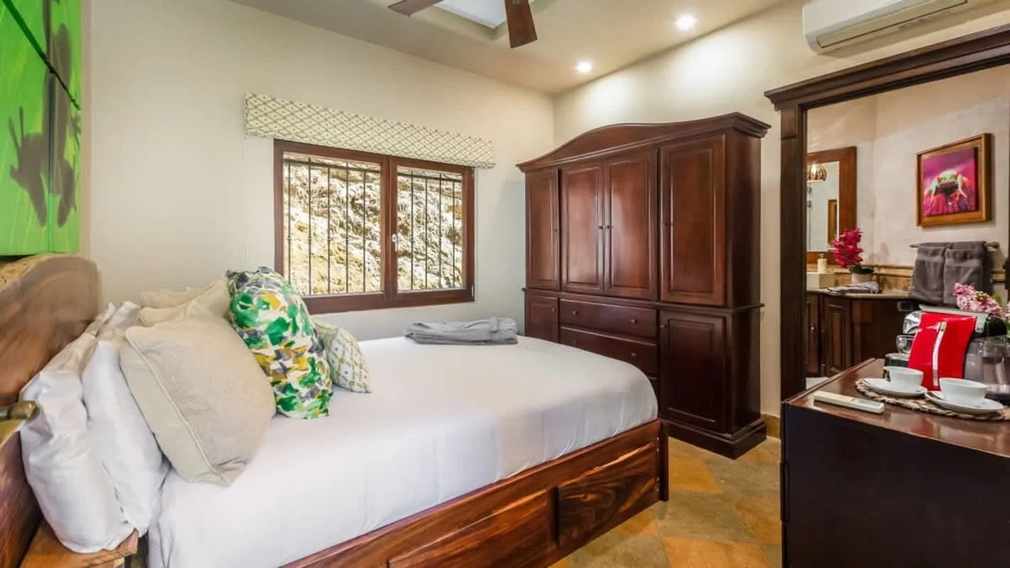 A bedroom with a bed beside a dark wooden wardrobe and a window.