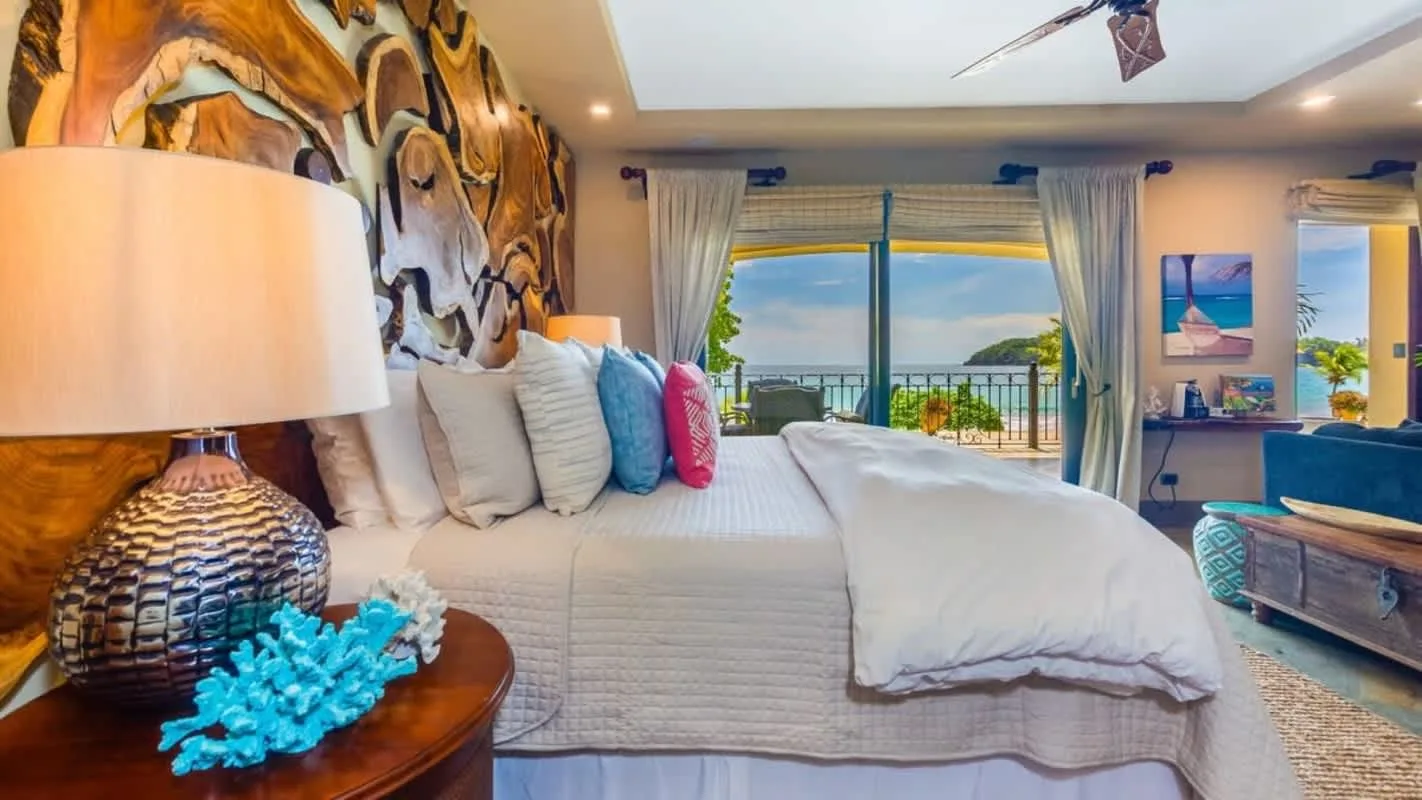 A bedroom with a bed facing wide glass doors and a balcony view.