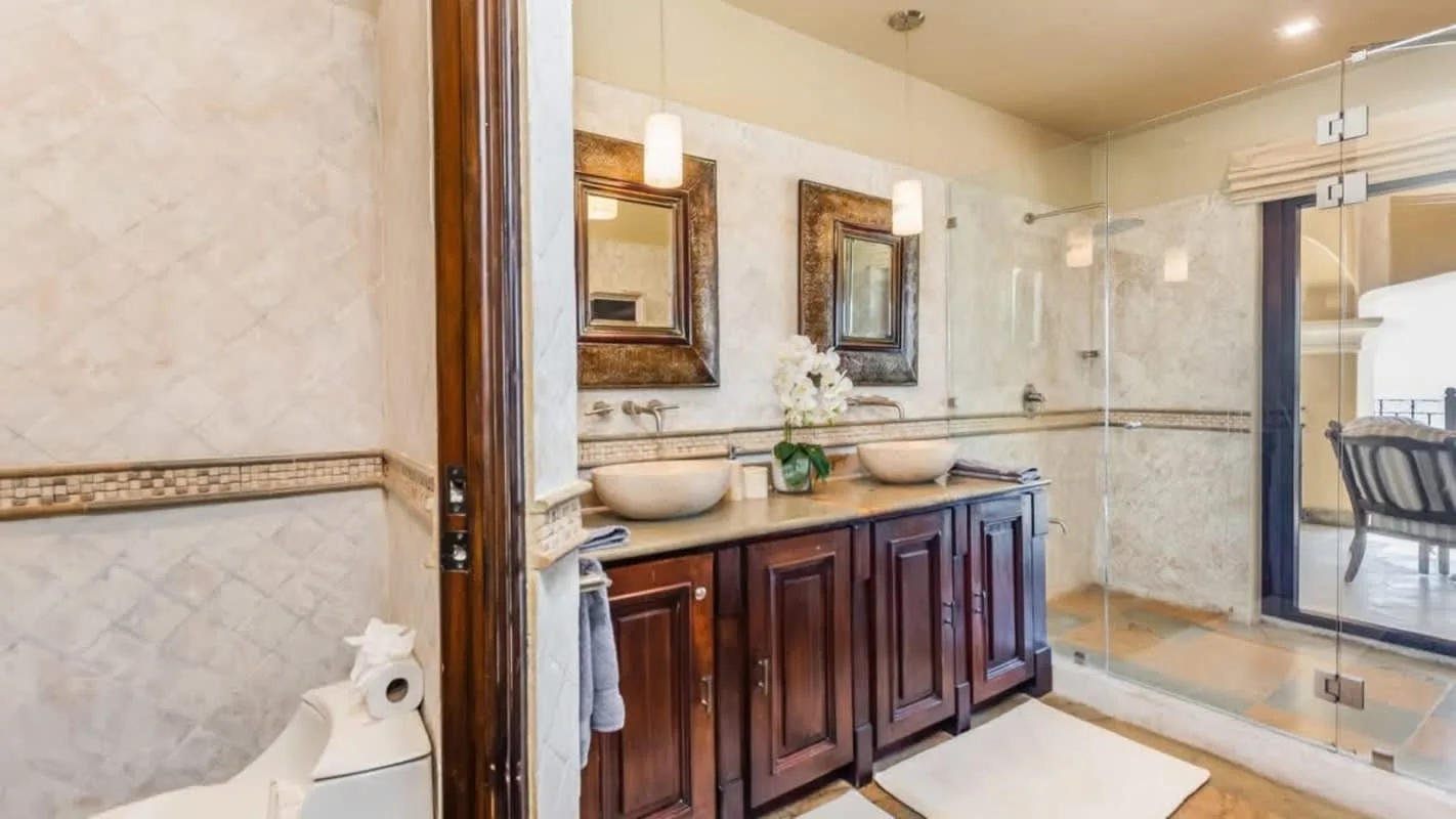 A bathroom with a double vanity, mirrors, and a glass shower.