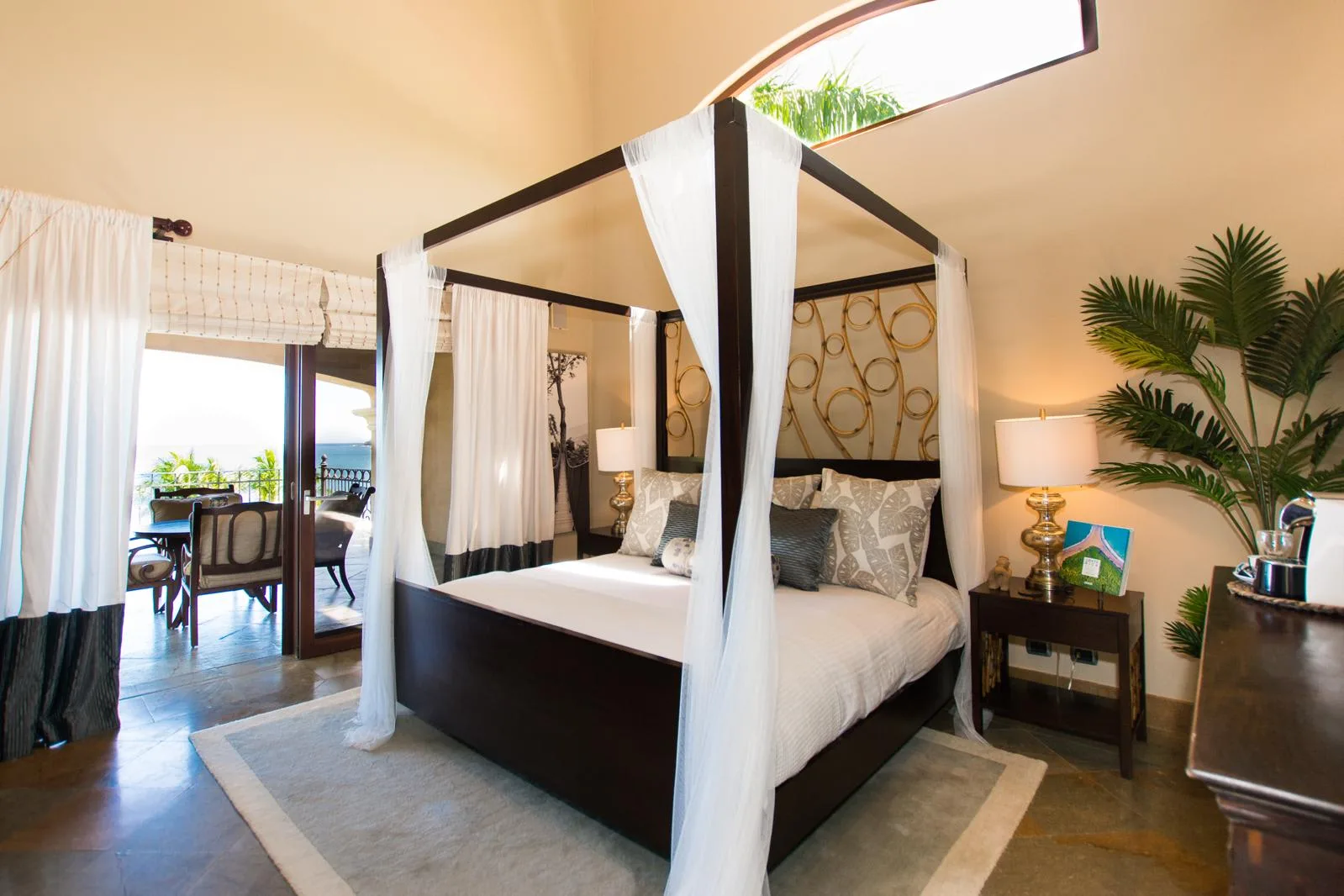 A bedroom features a canopy bed with white drapes and a bedside table.