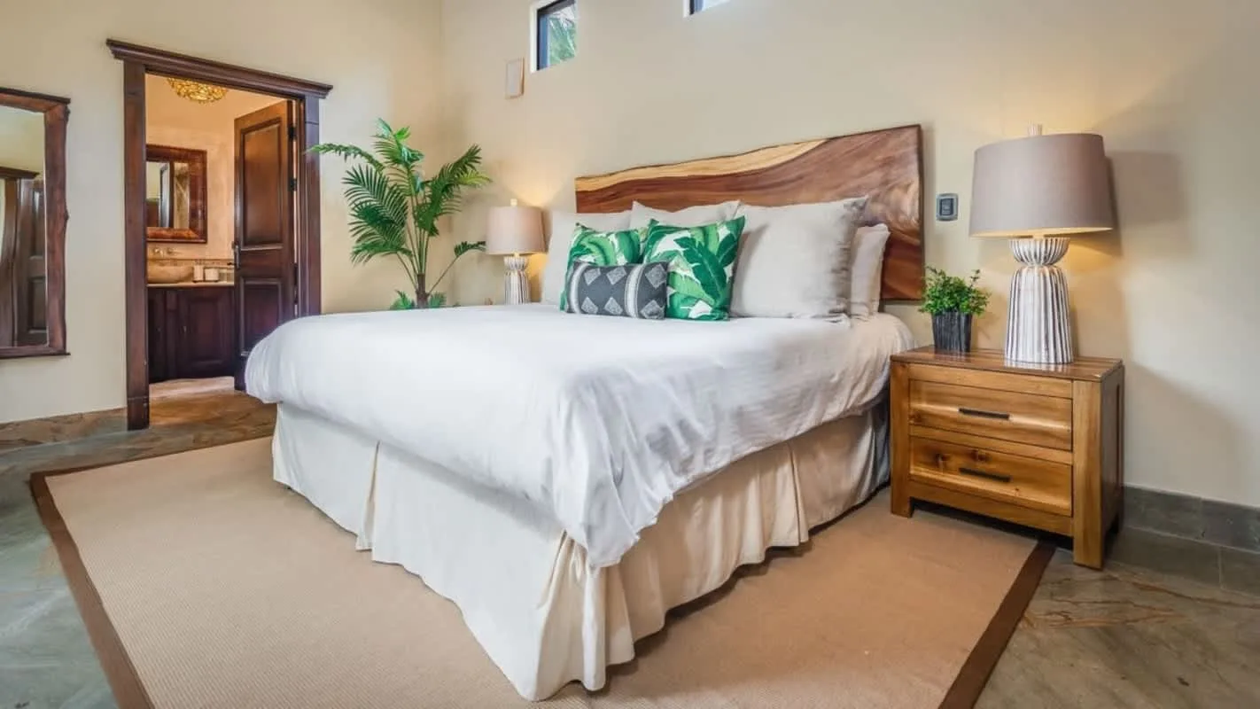 A bedroom with a neatly made bed and a wooden bedside table.