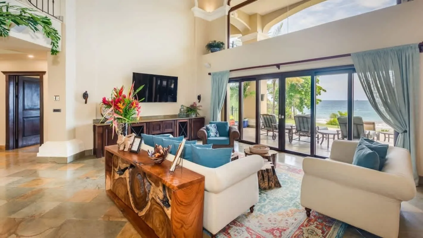 A bright living room with seating arranged around a wooden coffee table and glass doors.