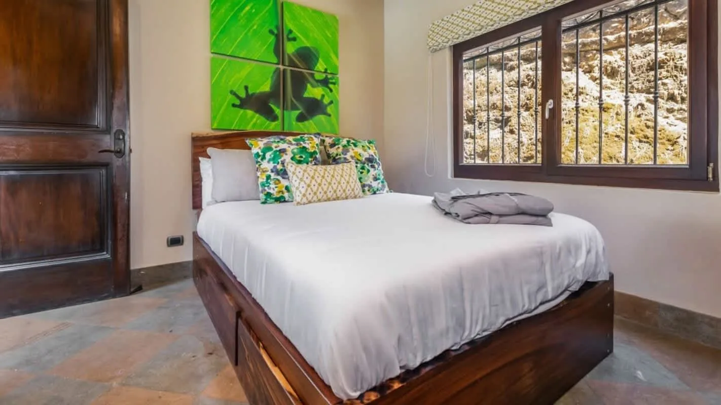 A bedroom with a neatly made bed and a large window.
