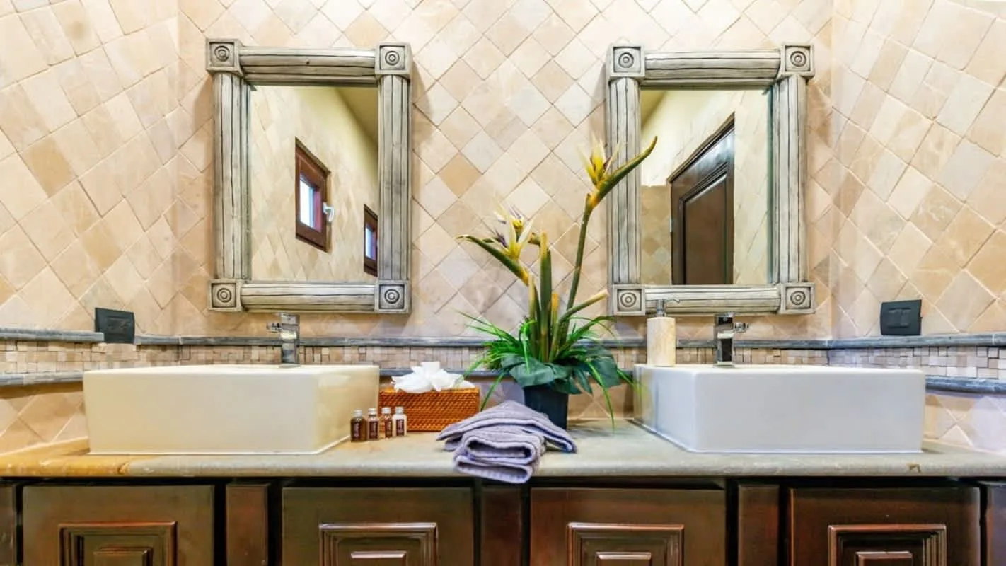 A bathroom vanity with two sinks, framed mirrors, and flowers.