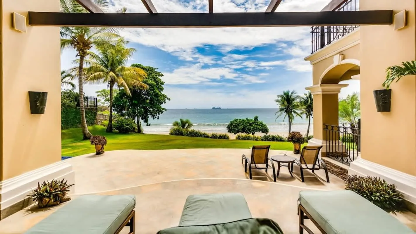 An open patio overlooks palm trees, greenery, and the ocean.