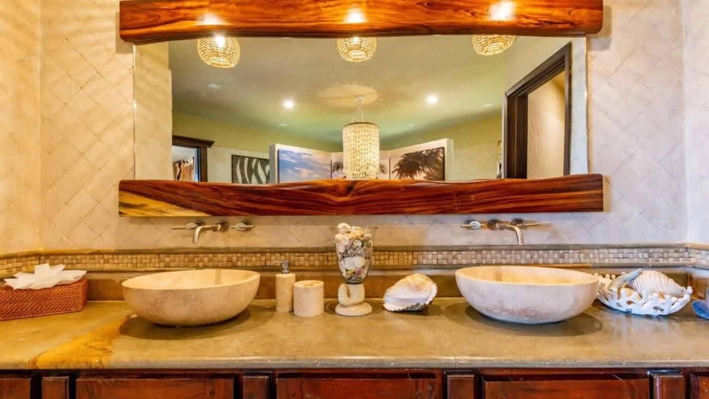 A bathroom vanity with a wide mirror and two vessel sinks.