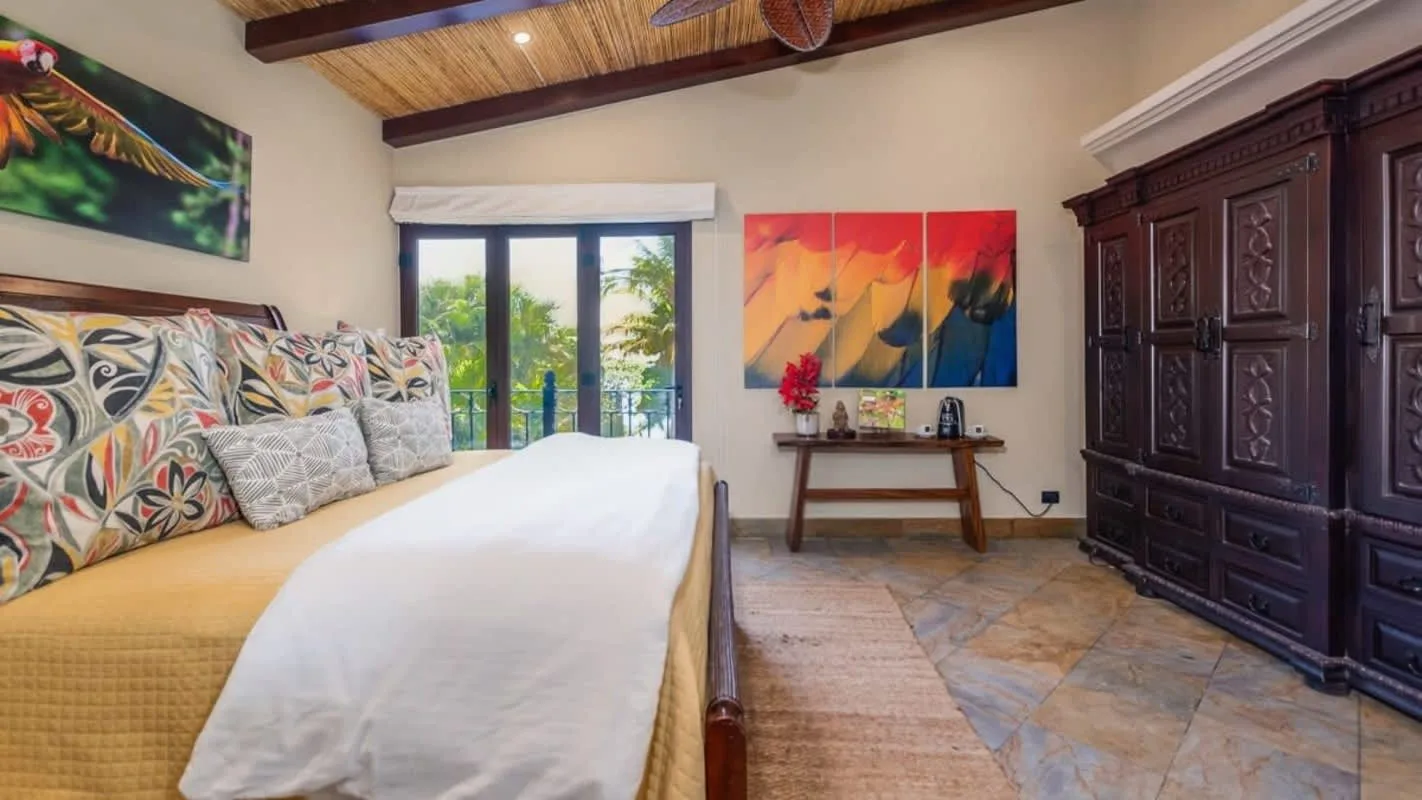 A bedroom with a bed, colorful wall art, and a dark wooden cabinet.