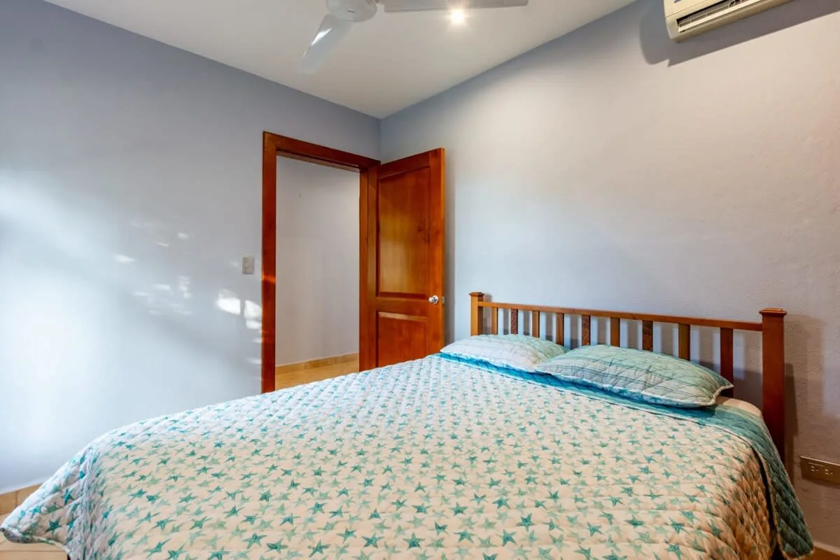 A bedroom with a bed covered in a patterned bedspread and an open wooden door.