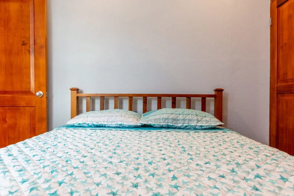 A bedroom with a wooden bed, two pillows, and patterned bedding.