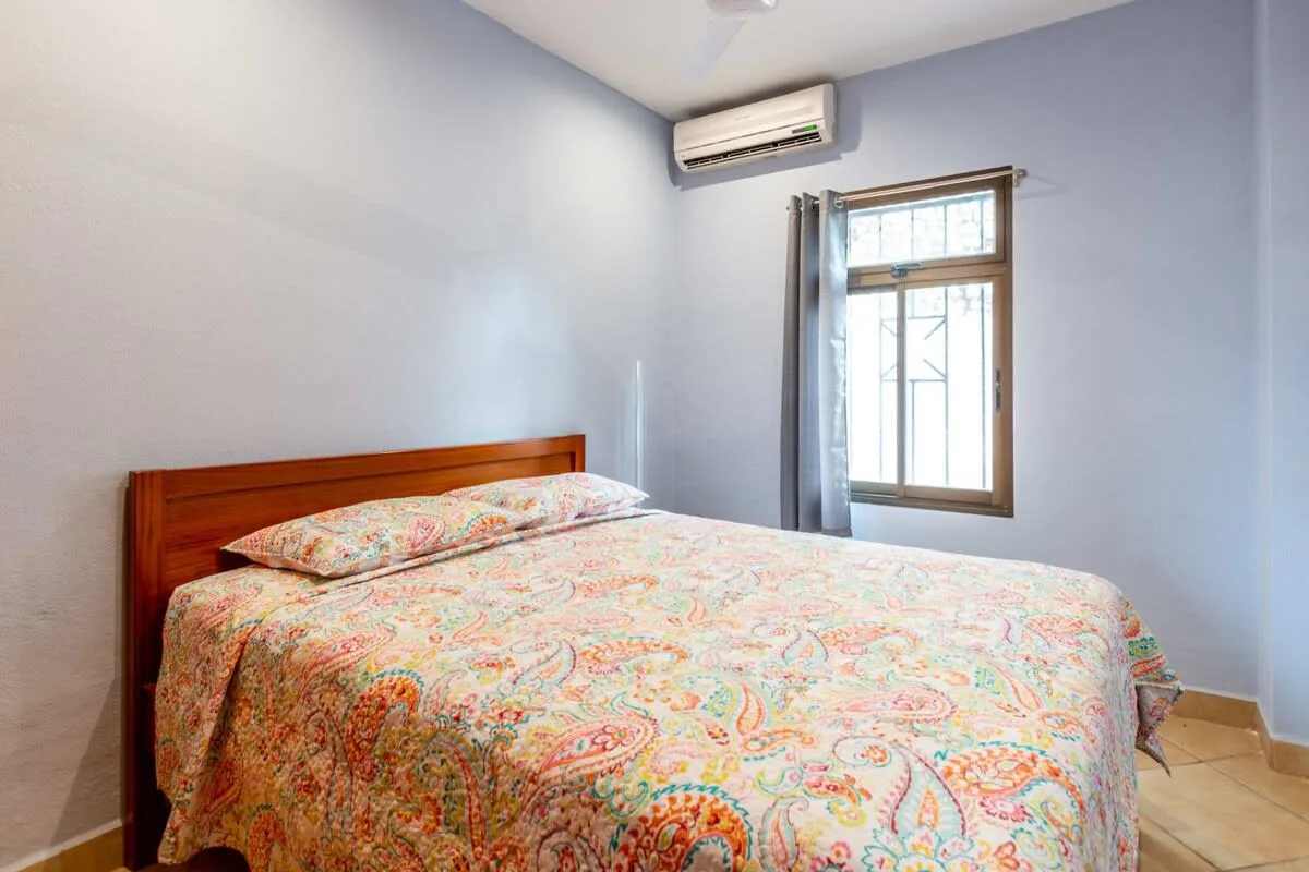 A bedroom with a bed covered by a colorful patterned bedspread.
