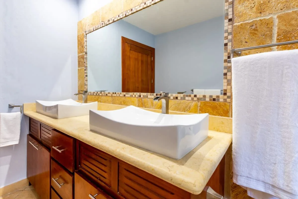 A bathroom vanity with two sinks sits beneath a large mirror.