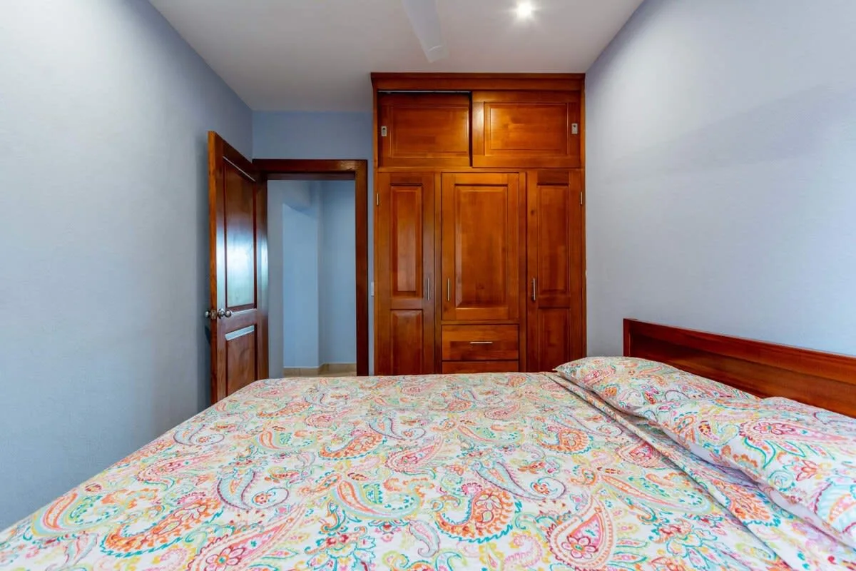 A bedroom with a patterned bedspread and a wooden wardrobe.