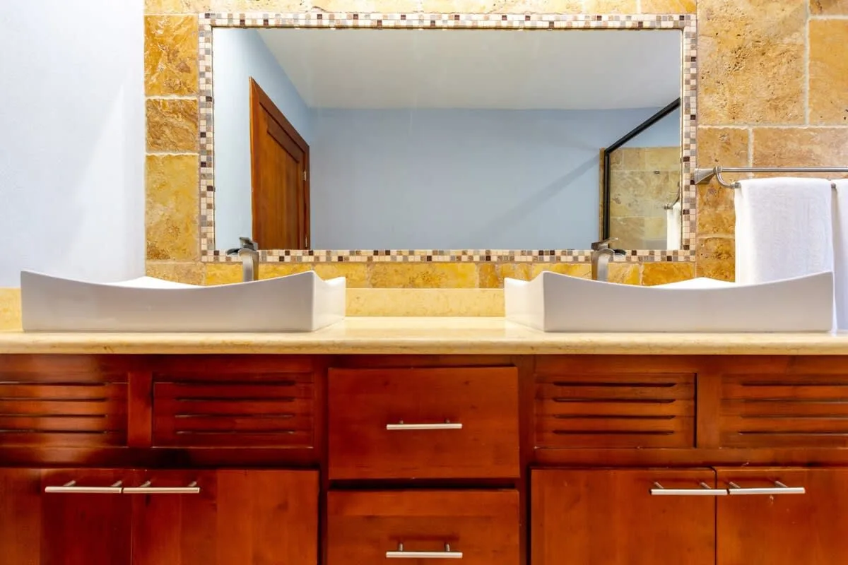 A bathroom vanity with two sinks sits beneath a large mirror.