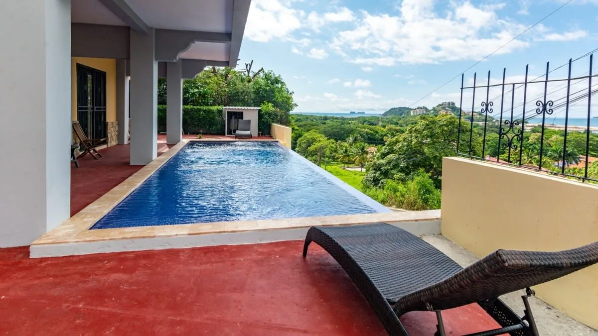 Shared amenity: Outdoor pool beside a covered patio, with surrounding greenery.