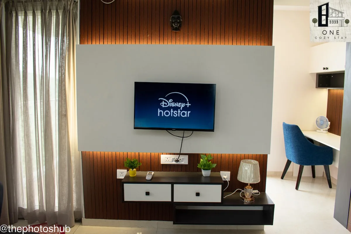 Interior de una habitación con un televisor montado en la pared sobre una consola baja.