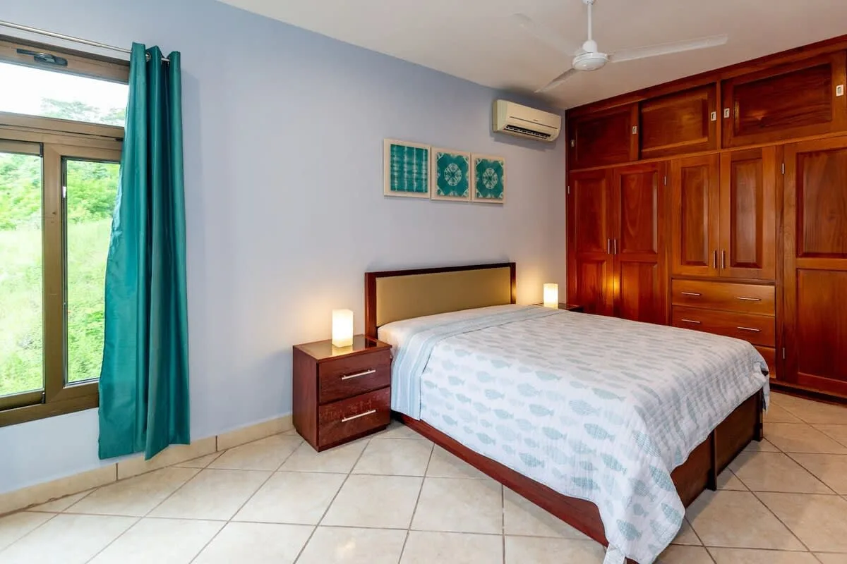 Un dormitorio con una cama, armarios de madera y una ventana con cortinas.