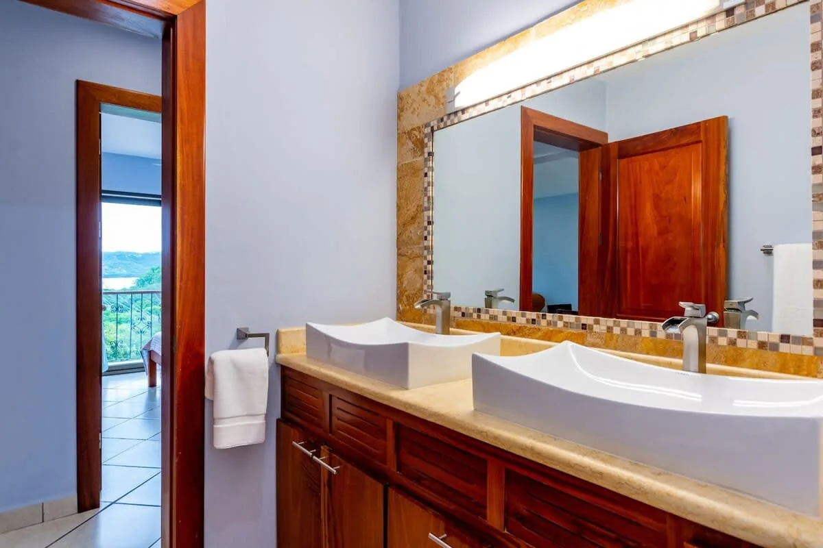 Un lavabo de baño con dos lavabos y un espejo grande.