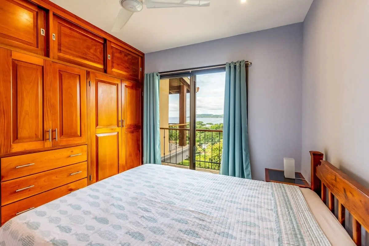Un dormitorio con una cama, armarios de madera empotrados y una puerta al balcón.